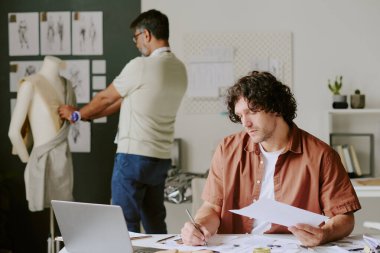 Yetenekli tasarımcı çizimi yaparken çok yetenekli terziler de gelecekteki elbiseler üzerinde dart oynuyor.
