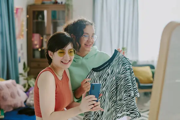 stock image Two teenagers smiling while choosing clothes together in room with wardrobe in background smiling at camera