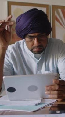 Türban dönen kalemli Hintli erkek kafası ve şirket geliştirme için yeni bir plan düşünürken tablet iş istatistiklerini gözden geçiriyor