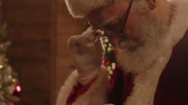 Noel Baba kostümü giyen son sınıf beyaz erkeklerin Noel için dekorasyon yaparken Noel çorabını dikkatlice asmaları yakın çekim.