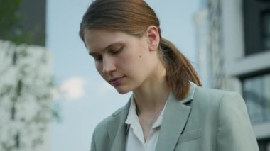 Kafkasyalı genç iş kadınının, açık havada dijital tablet üzerinde çalışırken, daracık takım elbise giydiği yakın çekim.