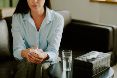 Kanepede oturan bir kadın elinde mendillerle, masasının yanında suyla, sıcak, kapalı bir ortamda, kasvetli bir ruh halini yansıtan.