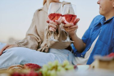 Ön planda bulanık bir arka plan ve yiyecekle açık hava pikniğinin tadını çıkaran iki kişi.