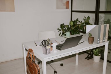 Ofis malzemeleri ve siyah laptop evdeki beyaz ahşap masada.