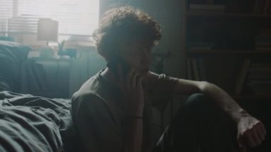 Genç bir adamın öfkeyle telefona bağırmasına ve yapılmamış yatağa atmasına, sonra da evde yerde otururken başını dizlerinin üstüne koymasına alındım.