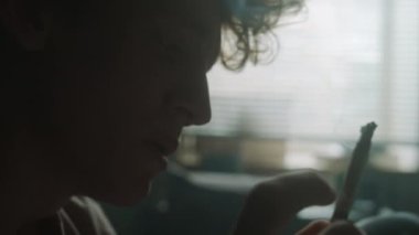 Üzgün bir gencin yatak odasına sigara külü attığı yakın plan bir fotoğraf.