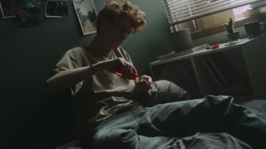 Çaresiz genç adam aniden ilaç şişesinden avuç içine beyaz haplar doldurup yatağa atıyor.