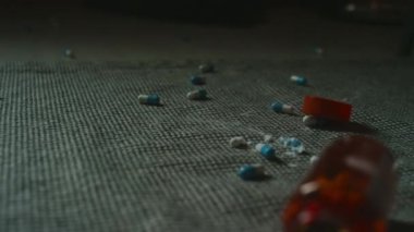 Yakın plan hiç kimse yatak odasındaki portakal rengi plastik şişeden dökülen kapsüllerin odak fotoğrafını çekmez.