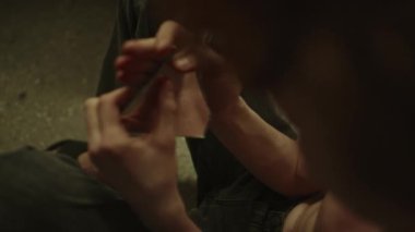 Çaresiz genç adamın yerde otururken aynada kendine baktığı yakın çekim görüntüsü.