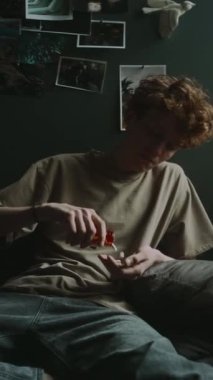 Harap olmuş genç bir adamın portakal şişesinden açık ele kapsülleri dökerken ve yumruklarını sıkarken dikey görüntüsü.