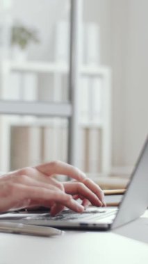 İyi ışıklandırılmış ofiste masa başında oturan ve dizüstü bilgisayarla çalışan işadamlarının dikey yakın görüntüsü