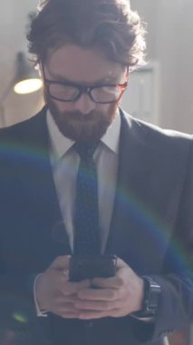 Resmi giysileri ve gözlükleri olan genç sakallı işadamının iş günü ofiste dikey fotoğrafı.