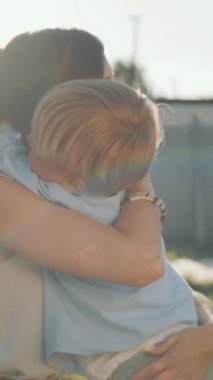 Küçük mutlu çocuğun boynuna sarılıp alnından öptüğü dikey bir sahne. Sonra arka bahçede kulaklarına dokunuyor.