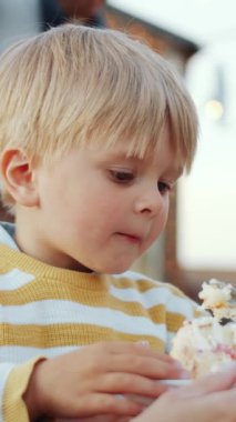 Küçük çocuğun açık hava aile partisinde nefis doğum günü pastası yerken dikey yakın çekimi.