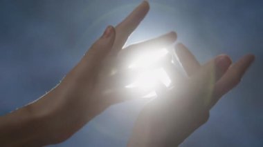 Kadın ellerinin yakın plan çekimi. Parlak spot ışıkları önünde parmakları birbirine dolaştırıyor. Beyaz buhar yavaşça hareket ediyor.