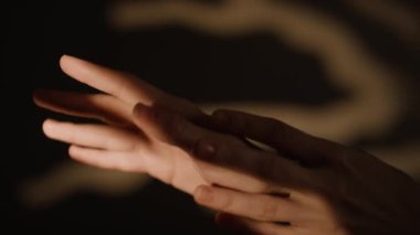 Bilinmeyen genç bir kadının elleri, dekoratif dalların ana hatlarıyla bulanık arka planda yumuşak hareketler yapıyor.