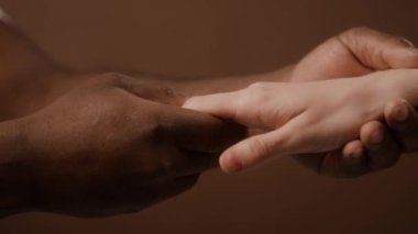Kafkas kadının parmaklarına ve bileklerine masaj yapan Afrikalı Amerikalı adamın yakın plan görüntüsü.