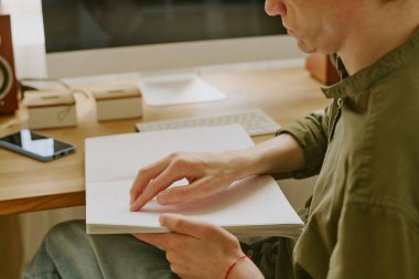 Braille kitabına odaklanmış, engelli, tanınmayan bir adamın yan görüntüsü.