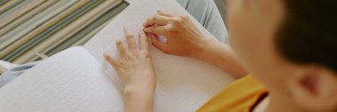 Tanımlanamayan bir kadının evde Braille kitabı okumaktan zevk aldığı tepeden tırnağa bir fotoğraf.