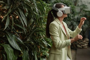 Yeni VR kulaklığı test eden tanınmayan genç bir kadının yan görüntüsü.