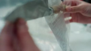 Analiz sırasında içinde bıçak olan kanıt torbası tutan tanınmayan suç laboratuarındaki bilim adamının ellerine yakından bakın.