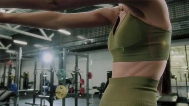 Spor sutyenli atletik bir kadın ve spor salonunda çalışırken omuzlarını, göğsünü ve yanlarını geren taytlar.
