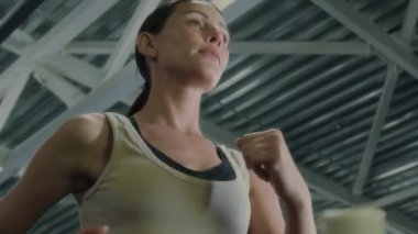 Spor kıyafetleriyle koşan ve spor salonunda egzersiz yaparken bir şişe su içen düşük açılı kadın odaklanma pozu.