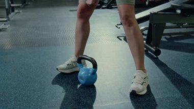 Spor kıyafetli genç güçlü bir kadının ağırlık kaldırma antrenmanında ağırlık kaldırma egzersizi yaparken çekilen pozu.