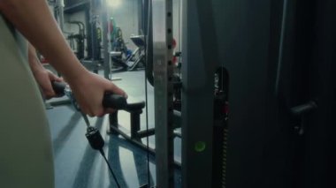 İyi donanımlı modern spor salonunda biseptik kablo kıvrımları yapan tanınmayan fit bir kadının yakın görüntüsü.