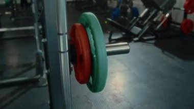 Spor salonunda yürüyen ve ağırlık kaldıran bir kadının güç egzersizine hazırlanırken görüntüsünü kapatın.
