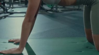Genç bir kadının çocuk pozunda esneme sahnesini yukarı kaldır, sonra da spor salonunda yoga yaparken yüzünü yukarı doğru çevir.