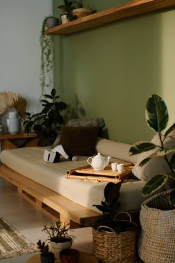 Dikey olarak, hiç kimse çaydanlık ve bardaklardan ahşap tepside ve Wabi-Sabi oturma odasındaki kanepede VR kulaklıkla vurulmaz.