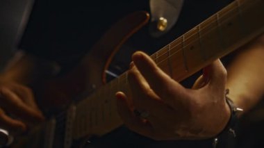 Kayıt stüdyosunda ya da konser salonunda canlı performans sırasında elektro gitar çalan tanınmayan olgun erkek müzisyenlerin ellerinin yakın çekimi