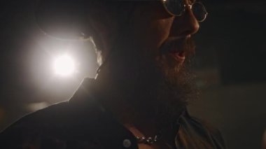 Stüdyoda şapka ve gözlük takan, müzik eşliğinde dans eden ve kadın davulcuyla dans eden beyaz erkek müzisyenlerin yakın çekimi.