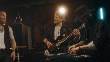 Kafkasyalı dört adamın müzik enstrümanları çaldığı ve dumanlı stüdyoda ya da konserde şarkı söylediği orta boy bir çekim.