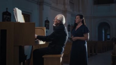Yaşlı müzisyenlerin boş katedralde çaldığı org eşliğinde sahne alan kadın opera sanatçısı.