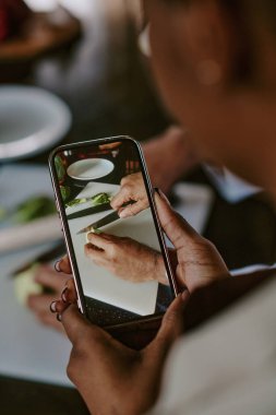 Sırtüstü uzanmış, elinde akıllı telefon tutan ve kabak soyan şefin videosunu çeken tanınmamış bir kadının fotoğrafı.