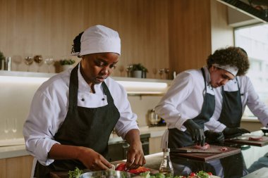 İş arkadaşları et keserken Afrika kökenli Amerikalı kadın aşçı limon dolması yapıyor.