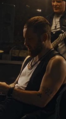 Canlı performanstan önce grupla prova sırasında şarkı listesine notlar alan dövmeli müzisyenin dikey çekimi.