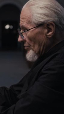 Siyah tişörtlü, org çalmayı bitirip kameraya bakan yaşlı bir müzisyenin dikey yakın çekimi.
