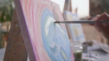 Sanat dersi sırasında deniz canlılarını tuvale fırçayla çizen kimliği belirsiz genç bir kadının yakın görüntüsü.