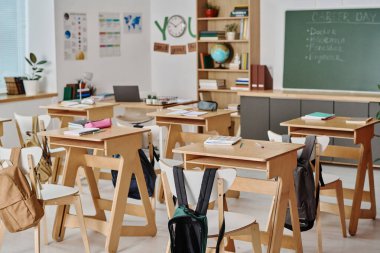 Modern sınıfın, içinde not defterleri, masalarda kalemler ve sandalyelerde öğrencilerin sırt çantaları olan iç çekimleri yok.