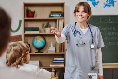 Neşeli Kafkas kadın doktor üniforma giyiyor. Sınıfta durmuş, okuldaki kariyeri hakkında konuşuyor.