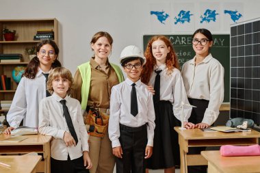 Mesleki rehberlik gününde sınıfta portre için poz veren bir grup genç öğretmen, kadın mühendis ve alfa öğrencisi.