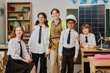 Bir grup alfa öğrencisi ve kadın mühendis okuldaki mesleki rehberlik gününde sınıfta portre için poz veriyorlar.