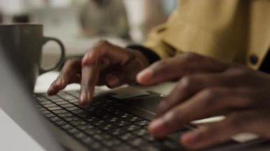 İş günü dizüstü bilgisayarda yazı yazan tanınmayan Afrikalı Amerikalı genç adamın yakın çekim görüntüleri.
