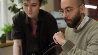 Erkek yöneticinin, masasının yanında duran genç bir iş arkadaşıyla iş planını tartışırken yakın plan görüntüsü.