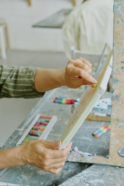 High angle shot of unrecognizable female hands holding white canvas and painting sketch with pastel chalk clipart