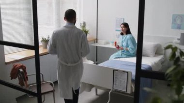 Estetik cerrah hastane koğuşuna giriyor, planlanan ameliyattan sonra genç bayan hastanın yüzünü gösteriyor ve ameliyat öncesi tavsiyeler veriyor.