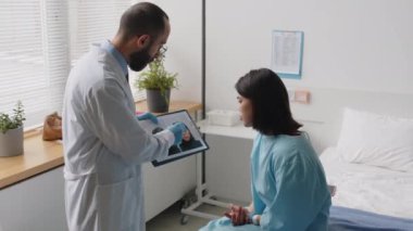 Estetik cerrah, genç bayan hastalara ameliyat öncesi ve sonrası görüntülerini gösteriyor ve klinikteki prosedür hazırlıkları sırasında yüzüne işaret kalemiyle çizgiler çiziyor.